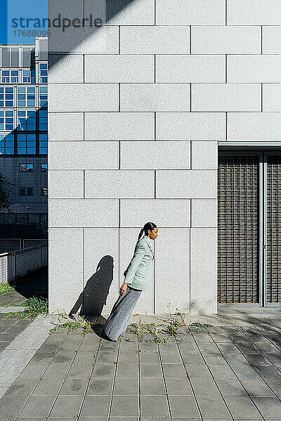 Junge Geschäftsfrau in schräger Position eines Bürogebäudes an einem sonnigen Tag