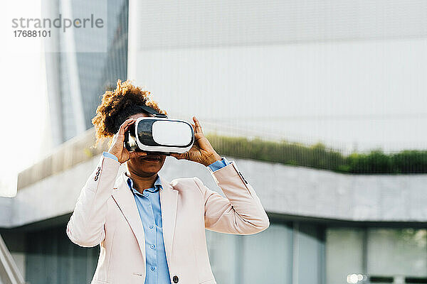 Geschäftsfrau trägt Virtual-Reality-Simulator vor Bürogebäude