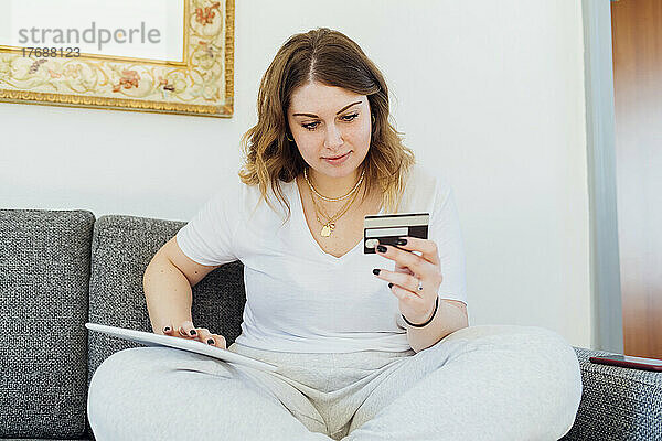 Lächelnde junge Frau  die per Kreditkarte auf einem Tablet-PC bezahlt