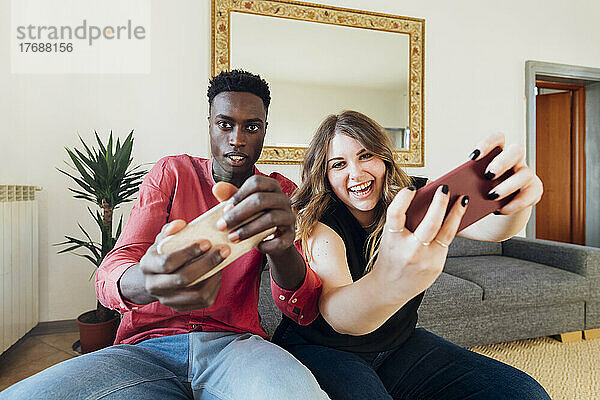 Glückliches Paar  das zu Hause Videospiele auf dem Smartphone spielt