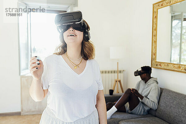 Glückliche Frau trägt Virtual-Reality-Simulator im Wohnzimmer