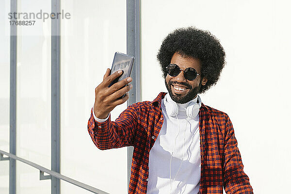 Glücklicher Mann mit Sonnenbrille  der ein Selfie mit dem Smartphone macht