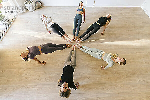 Women practicing yoga exercise in circle at fitness studio
