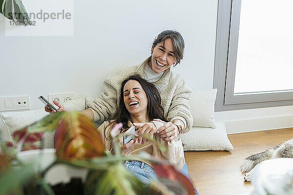 Glückliches lesbisches Paar mit Smartphone  das gemeinsam zu Hause genießt