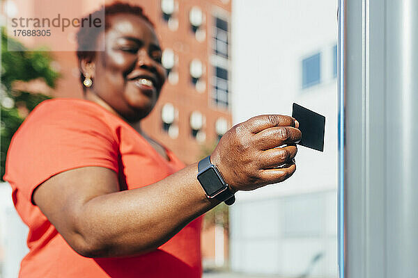 Lächelnde Frau  die an einem sonnigen Tag mit Kreditkarte bezahlt
