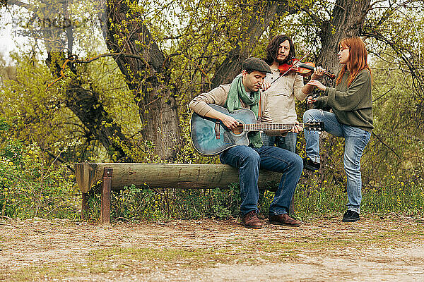 Künstler mit Musikinstrumenten üben in der Nähe einer Bank am Baum