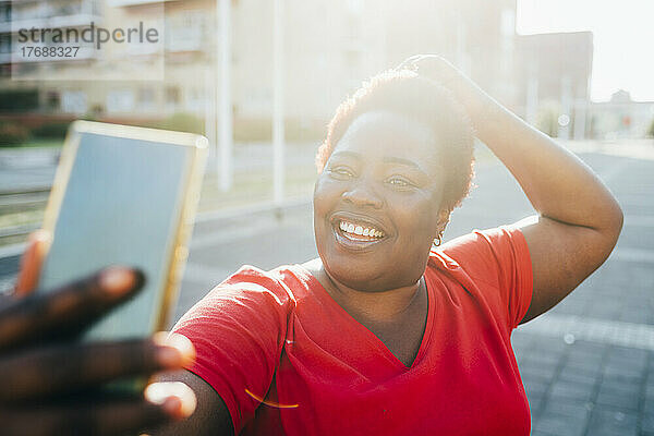 Glückliche Frau  die an einem sonnigen Tag ein Selfie mit dem Smartphone macht