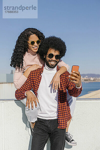 Glückliches Paar  das an einem sonnigen Tag ein Selfie mit dem Handy macht