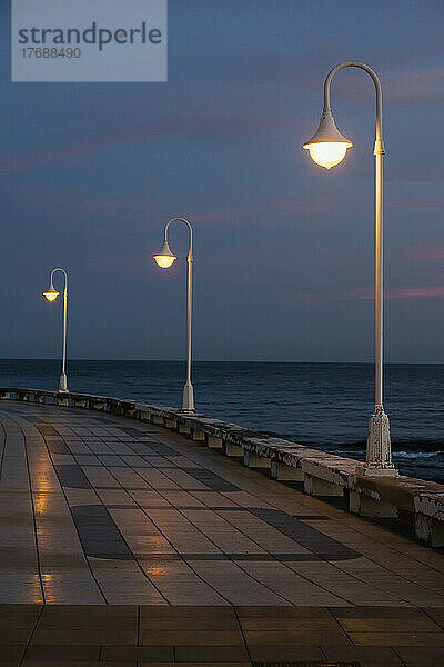 Beleuchtete Straßenlaternen an der Promenade am Meer