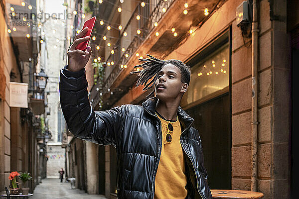 Junger Mann macht Selfie mit dem Handy in einer Gasse