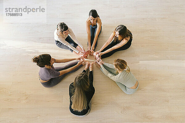 Women sitting in circle touching toes at yoga studio