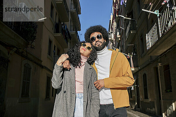 Ein Paar mit Sonnenbrille steht an einem sonnigen Tag in der Stadt