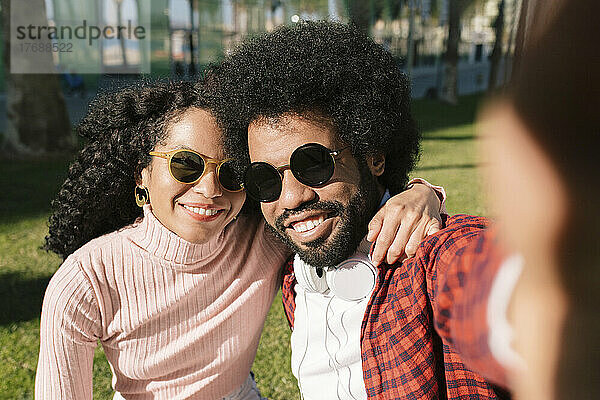 Glückliches Paar mit Sonnenbrille  das an einem sonnigen Tag ein Selfie macht