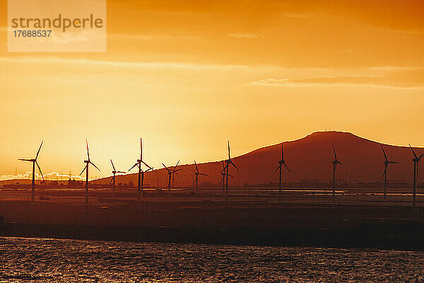 Silhouette Windkraftanlagen vor dem Berg bei Sonnenuntergang