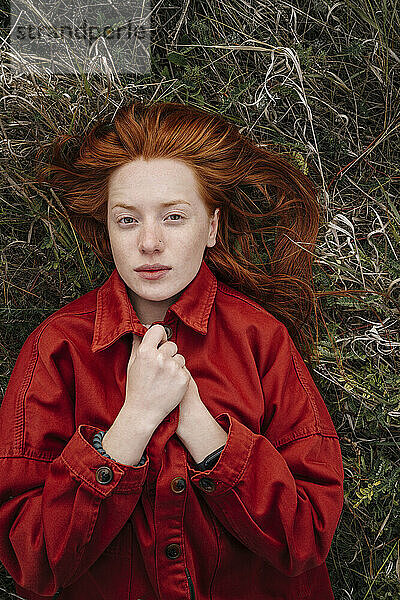 Young woman with redhead lying on grass field