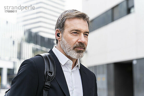 Reifer Geschäftsmann trägt kabellose In-Ear-Kopfhörer