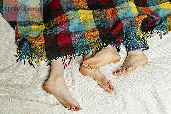 Feet of couple lying on bed