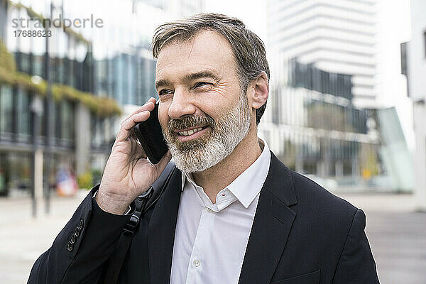 Lächelnder Geschäftsmann  der am Smartphone spricht