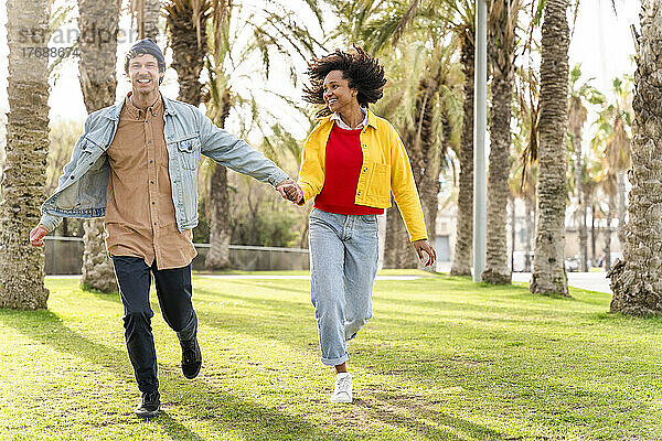 Cheerful couple running together at park