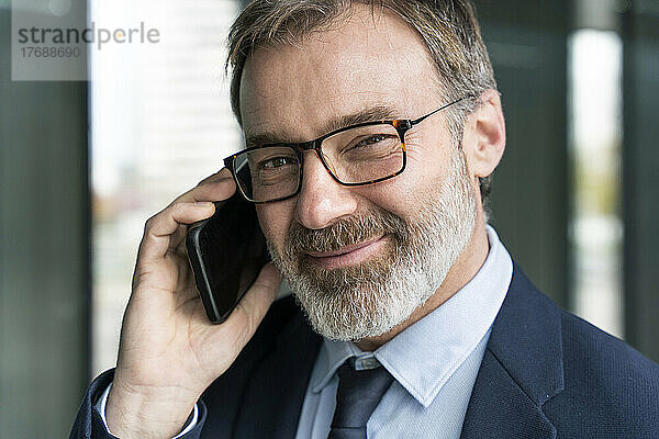 Reifer lächelnder Geschäftsmann  der am Handy spricht