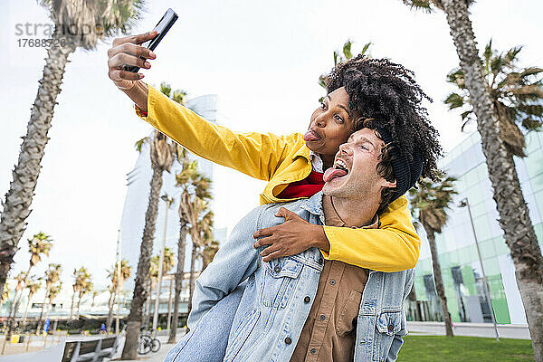 Paar streckt die Zunge heraus und macht ein Selfie mit dem Smartphone