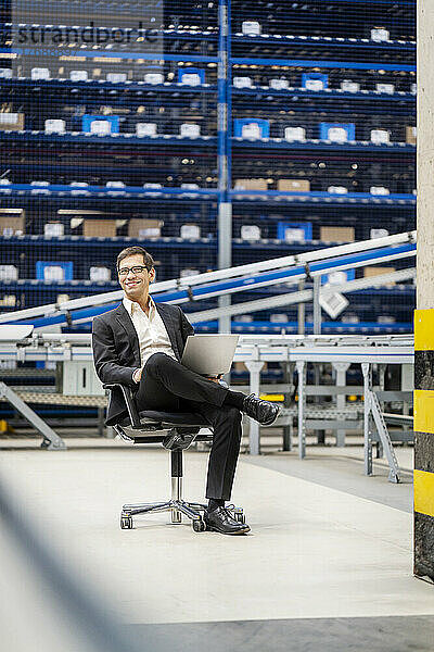 Reifer Geschäftsmann sitzt auf einem Stuhl in der Fabrik