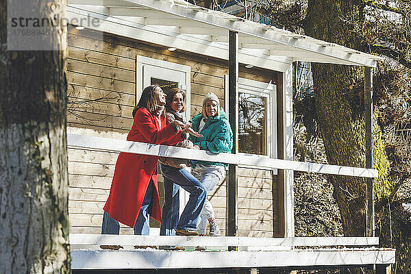 Freunde reden miteinander und stehen an einem sonnigen Tag auf der Terrasse