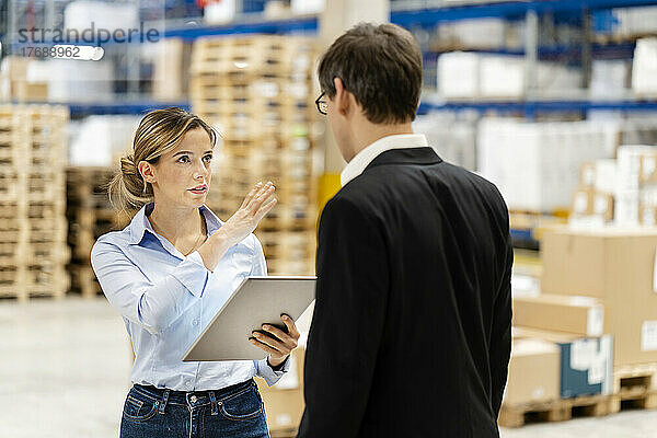 Junge Geschäftsfrau hält Tablet-PC mit Kollege in der Fabrik