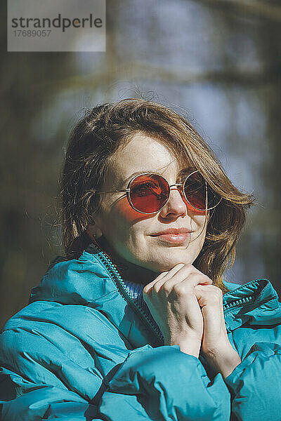 Junge schöne Frau mit braunen Haaren und Sonnenbrille an einem sonnigen Tag