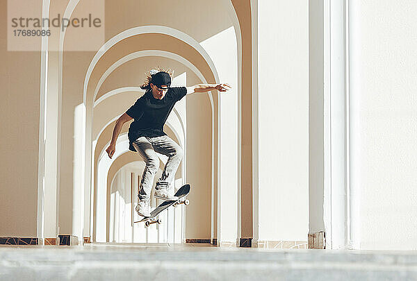 Mann übt Sprung mit Skateboard in Spielhalle