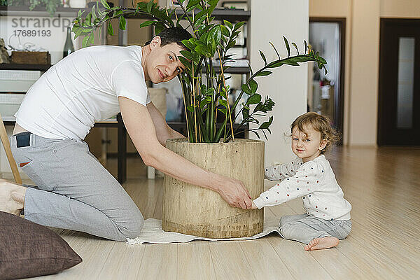 Vater und Tochter halten Topfpflanze im heimischen Wohnzimmer