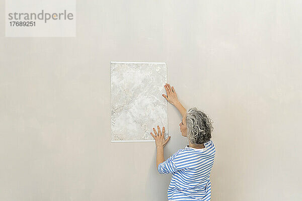 Frau analysiert Tapetenmuster an der Wand