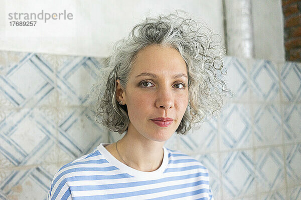 Frau mit grauen Haaren steht vor der Wand