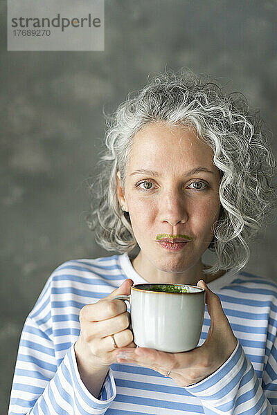 Frau mit Matcha-Tee-Schnurrbart hält Tasse