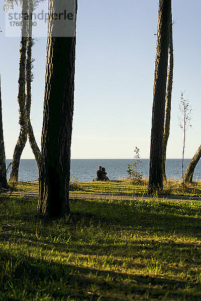 Ein Paar sitzt an einem sonnigen Tag vor der Küste