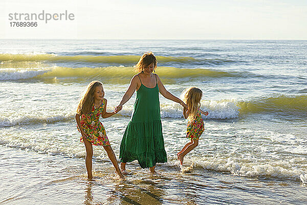 Mutter und Töchter spielen zusammen am Strand