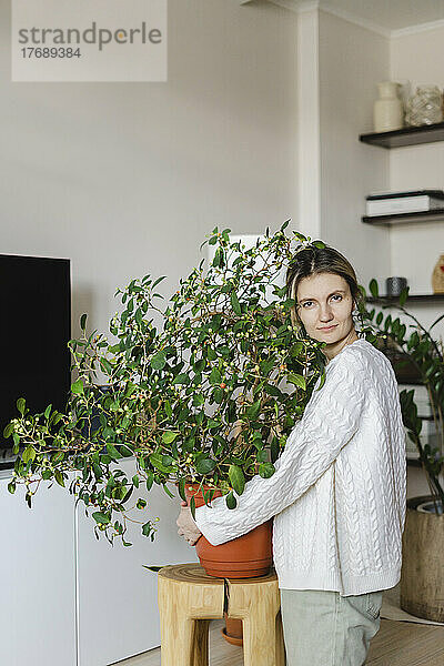 Frau umarmt Topfpflanze zu Hause