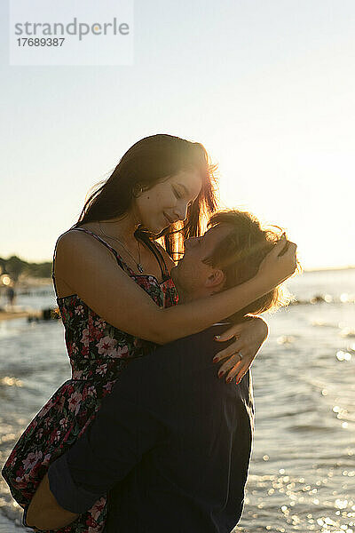 Junges Paar umarmt sich an einem sonnigen Tag am Strand