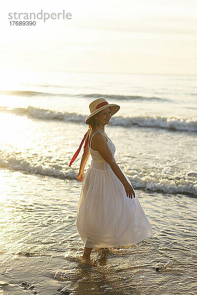 Glückliche Frau mit Hut am Strand