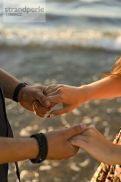 Paar hält Händchen am Strand an einem sonnigen Tag