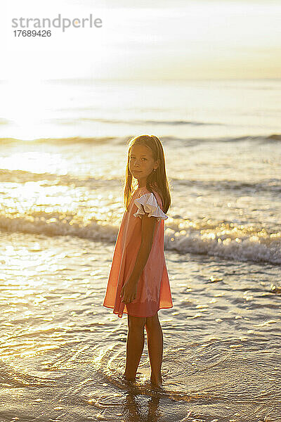 Mädchen steht an einem sonnigen Tag am Strand
