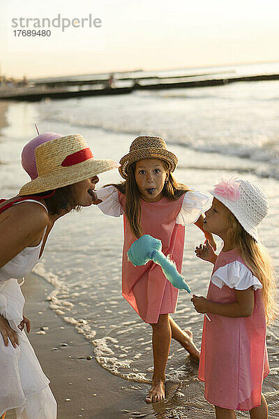 Mutter mit Töchtern  die am Strand die Zunge herausstrecken