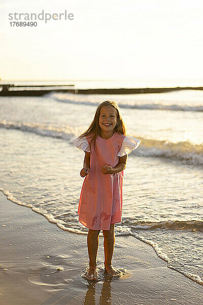 Glückliches Mädchen  das am Strand vor dem Meer steht