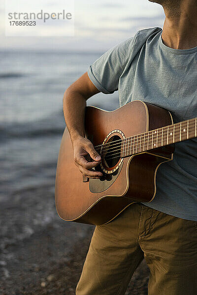 Mann spielt Gitarre am Strand