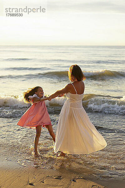 Glückliche Tochter  die mit Mutter am Strand genießt