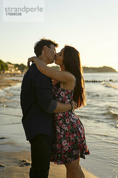 Liebevolles Paar küsst sich am Strand