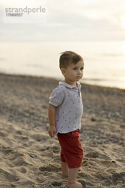 Cute baby boy standing at beach