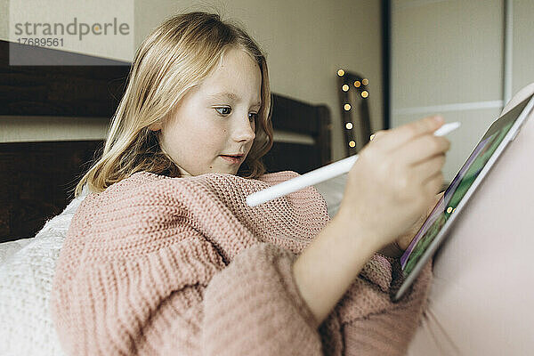 Mädchen mit digitalisierter Federzeichnung auf Tablet-PC zu Hause