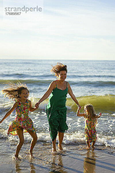 Glückliche Mutter und Töchter genießen den Strand