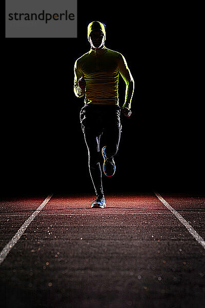 Young man jogging on running track at night
